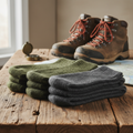 Thick merino wool survival socks in olive green and charcoal displayed with hiking boots