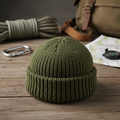 Tactical olive green wool survival beanie on rustic wooden surface