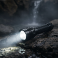 Military-grade waterproof tactical flashlight in matte black with visible beam of light